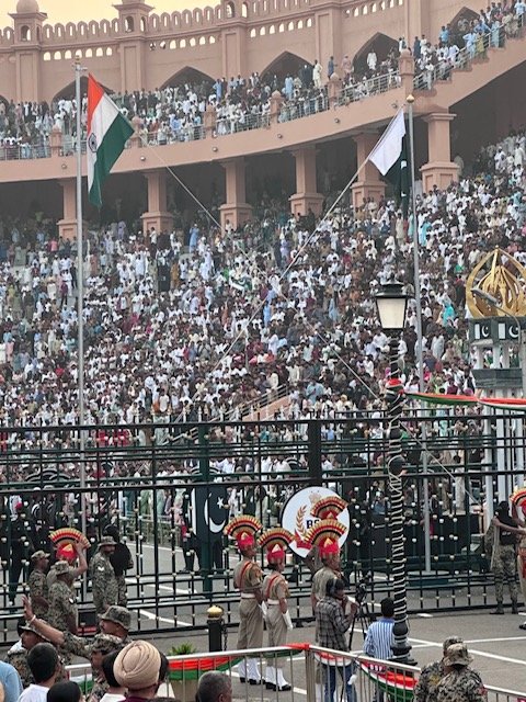 The Indian and Pakistani flags being lowered in the Beating Retreat ceremony, with BSF guards and crowds on both sides of the border
