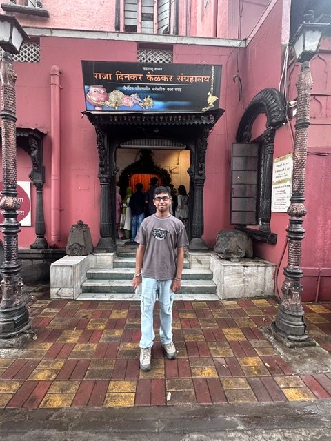 Standing at the entrance of the Raja Dinkar Kelkar Museum in Pune, beneath the sign in Devanagari script
